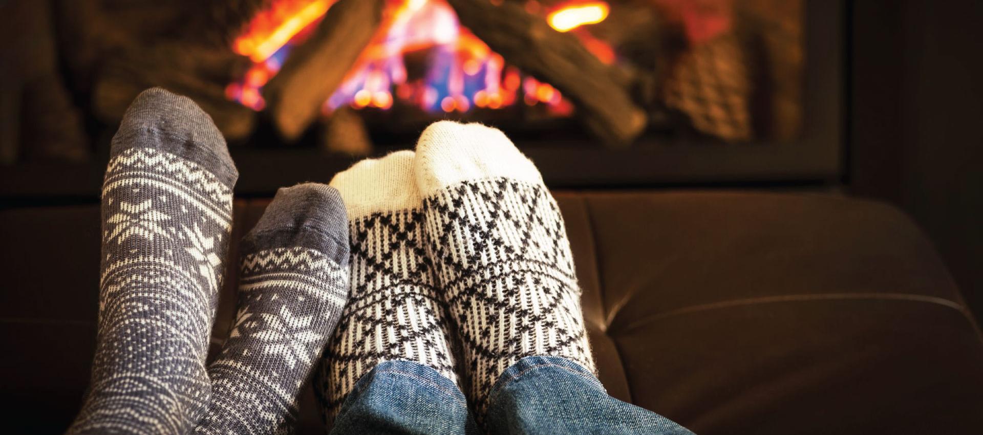 a pair of feet in warm socks in front of a fireplace