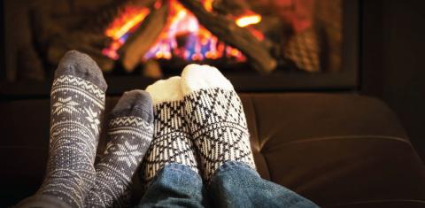 a pair of feet in warm socks in front of a fireplace